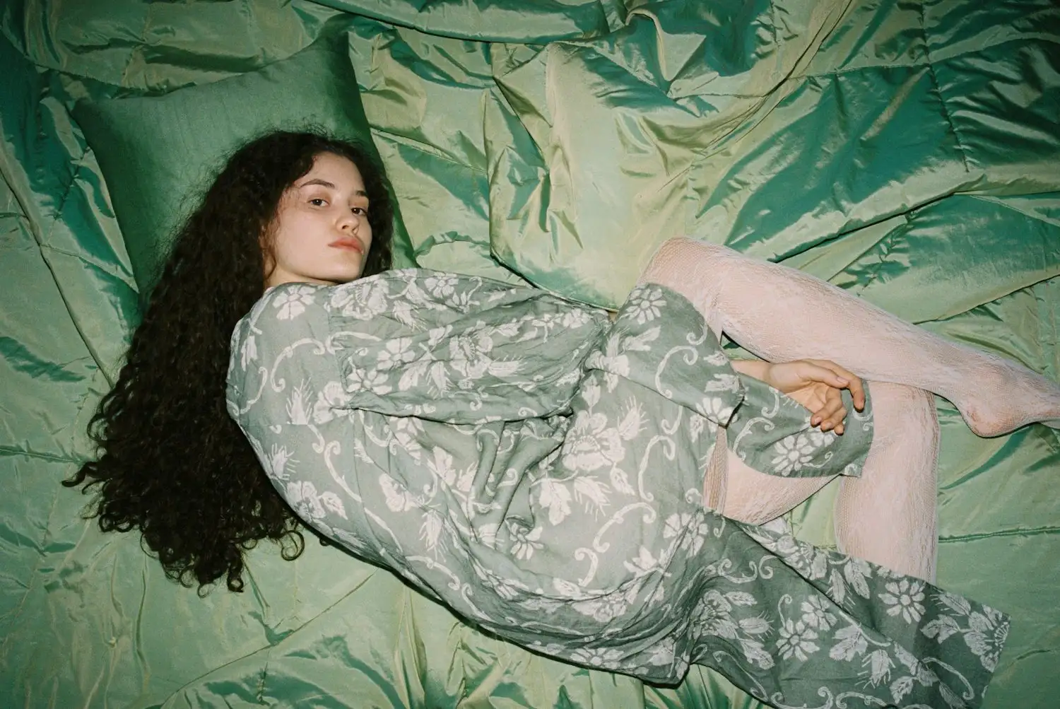 a young woman laying on a green blanket