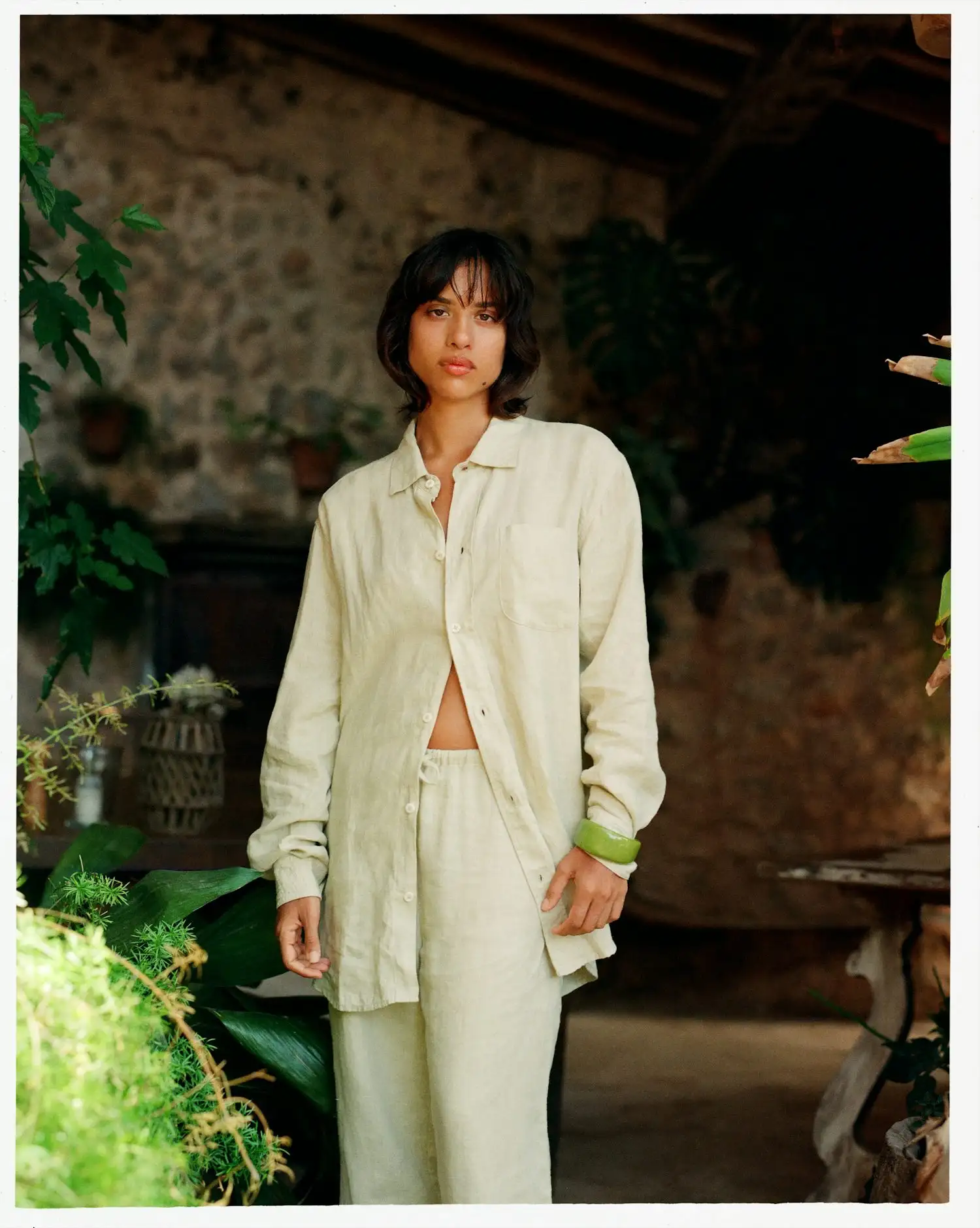 a woman in a white shirt and pants standing in a garden